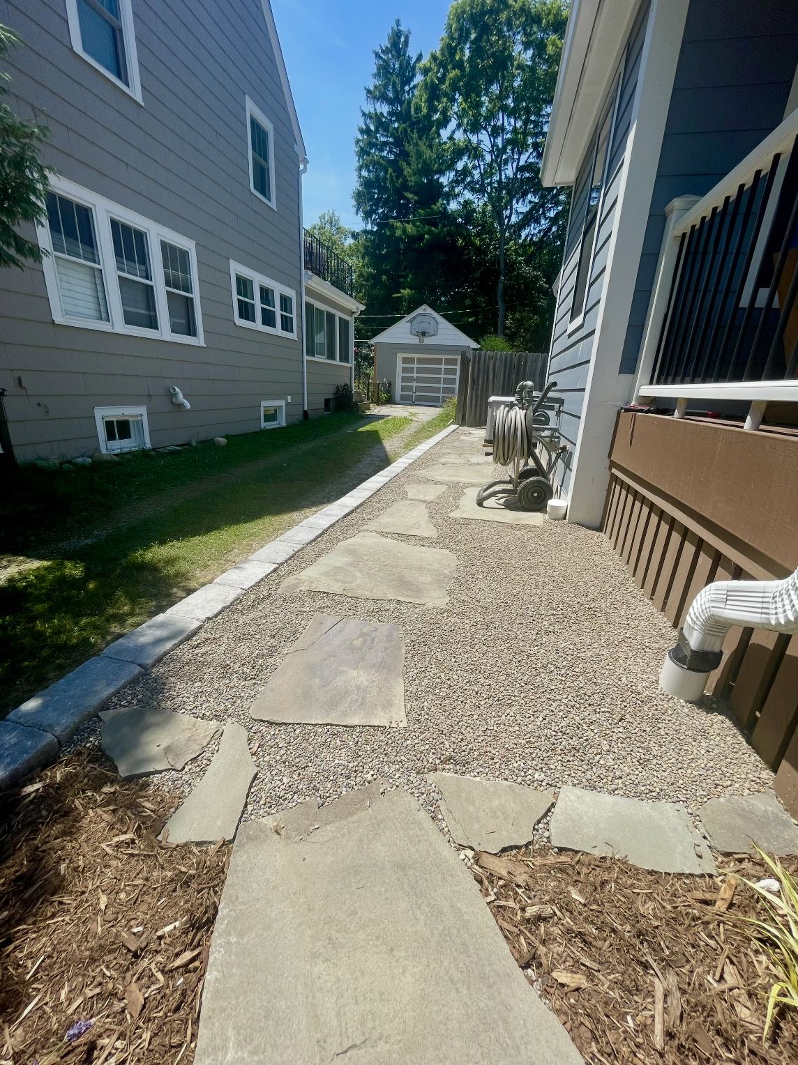Pea gravel and flagstone side-yard path with granite cobble edging between two Ann Arbor houses