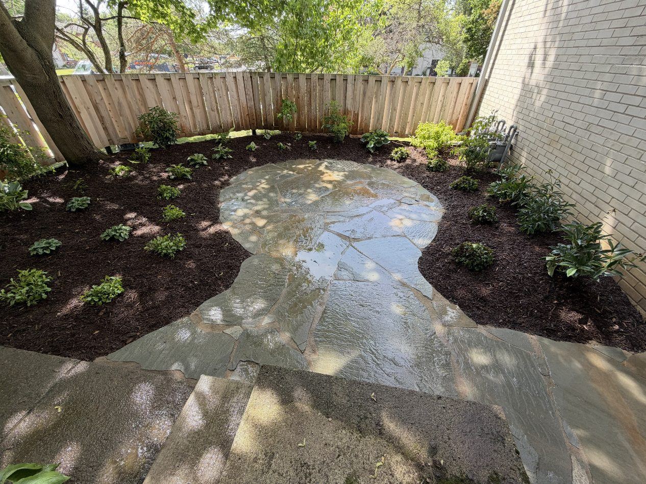 Curved flagstone patio and new shade plantings inside a cedar-fenced courtyard