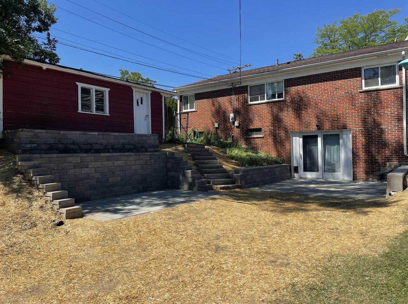 Terraced retaining walls, stone steps, and a new patio replacing the overgrown hillside