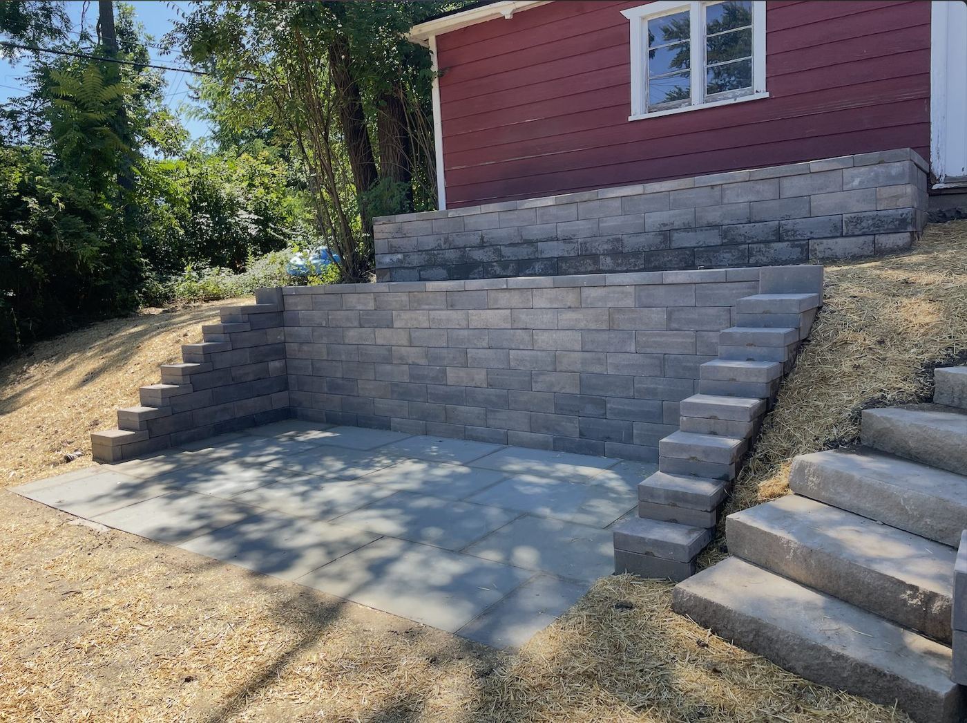 Bluestone patio framed by terraced block retaining walls and natural stone steps