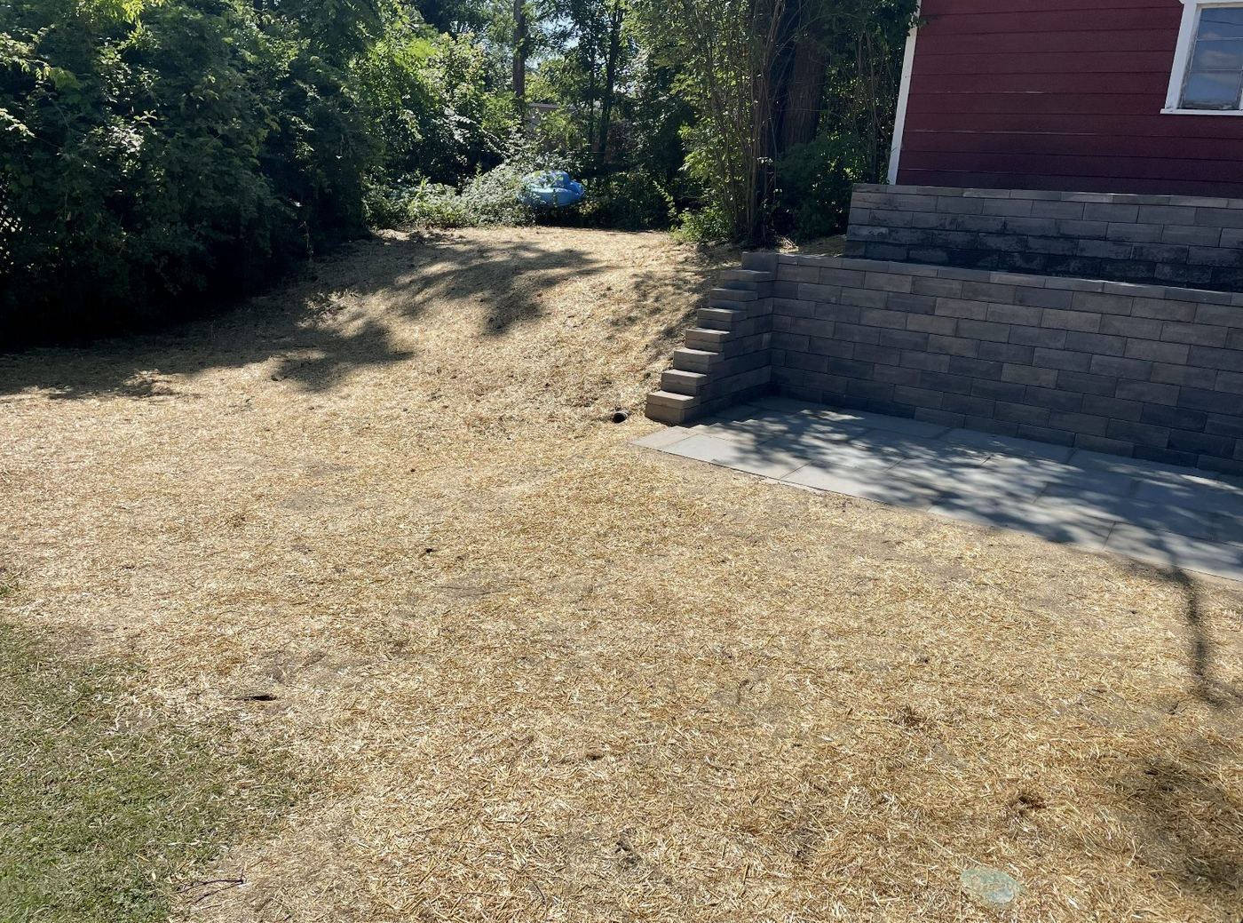 Retaining wall corner and stone steps on a freshly graded and seeded slope