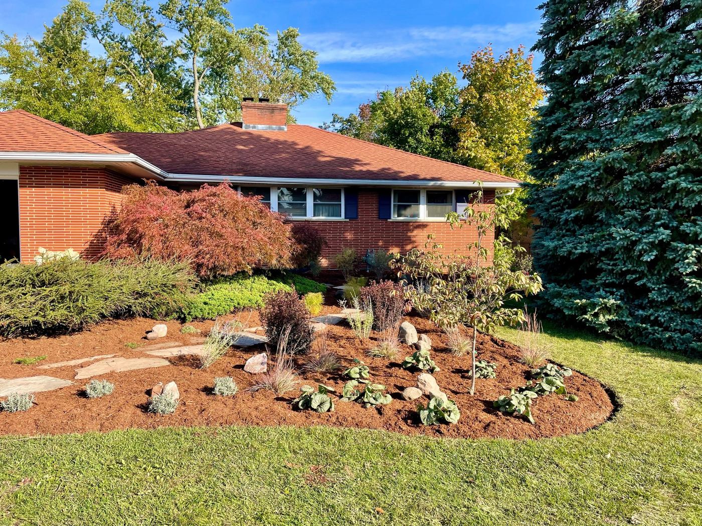 Finished front bed after garden makeover, with boulders and new plantings
