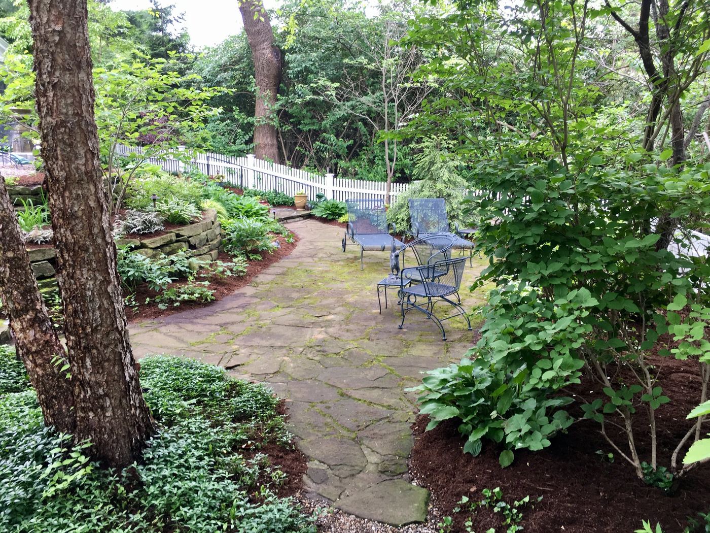 Finished stone patio with seating along a white picket fence