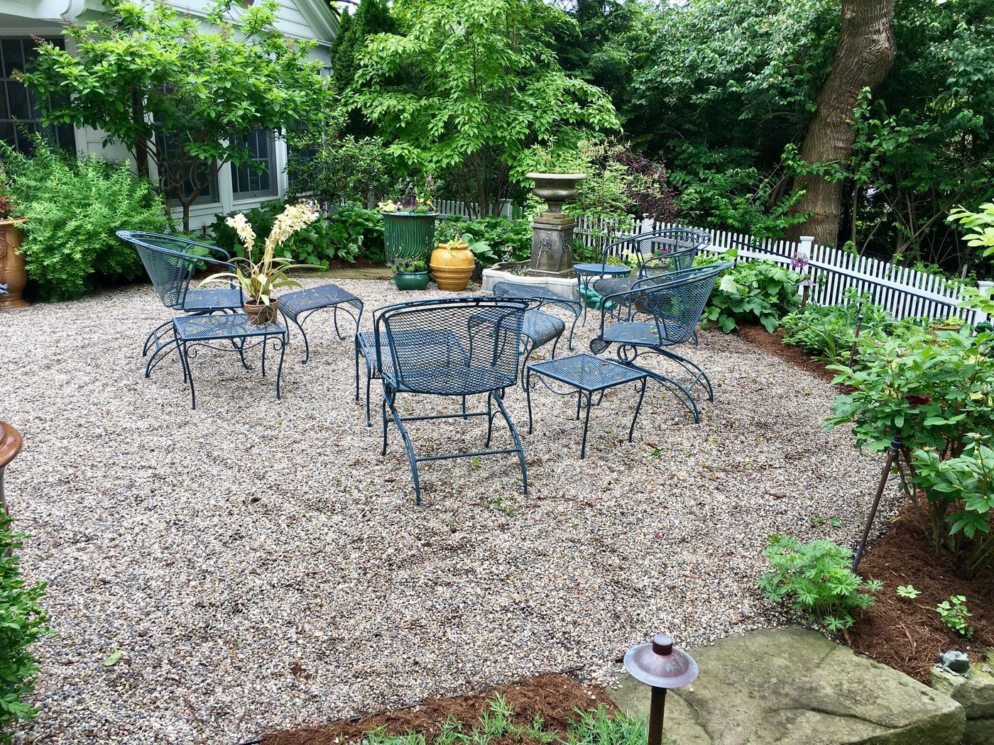 Gravel patio lounge area framed by mature plantings
