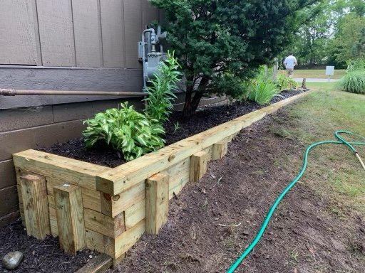 Layered timber raised bed along home foundation