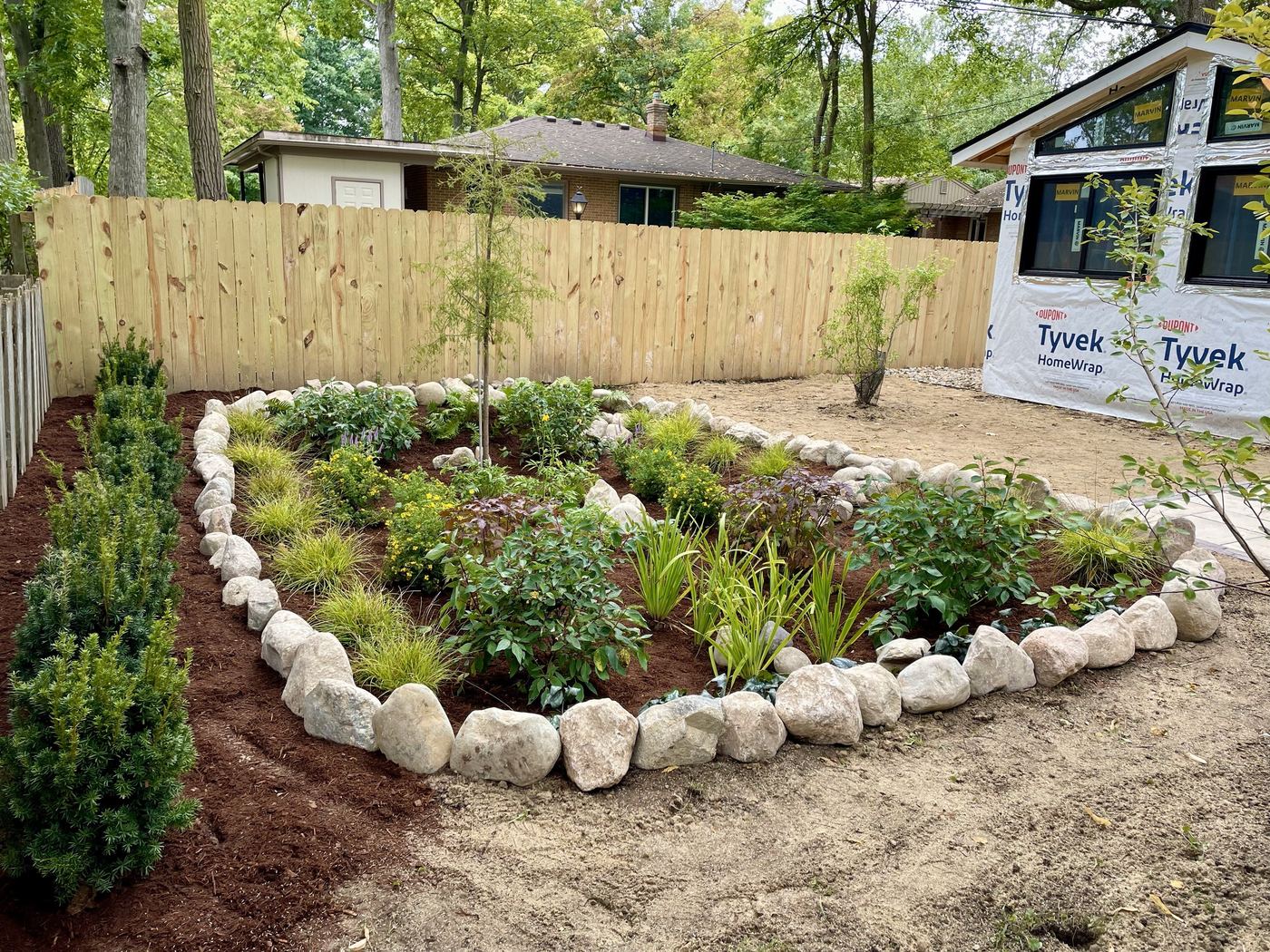Finished rain garden bed with river rock border and new plantings