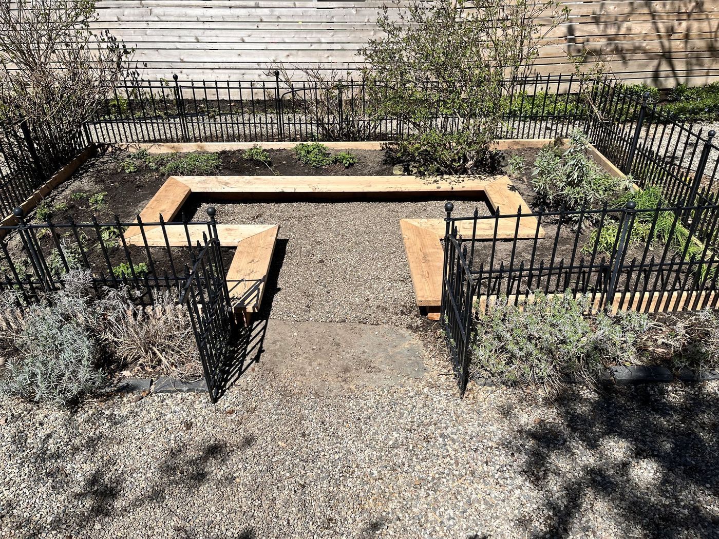 Wood-framed raised bed inside wrought-iron garden enclosure