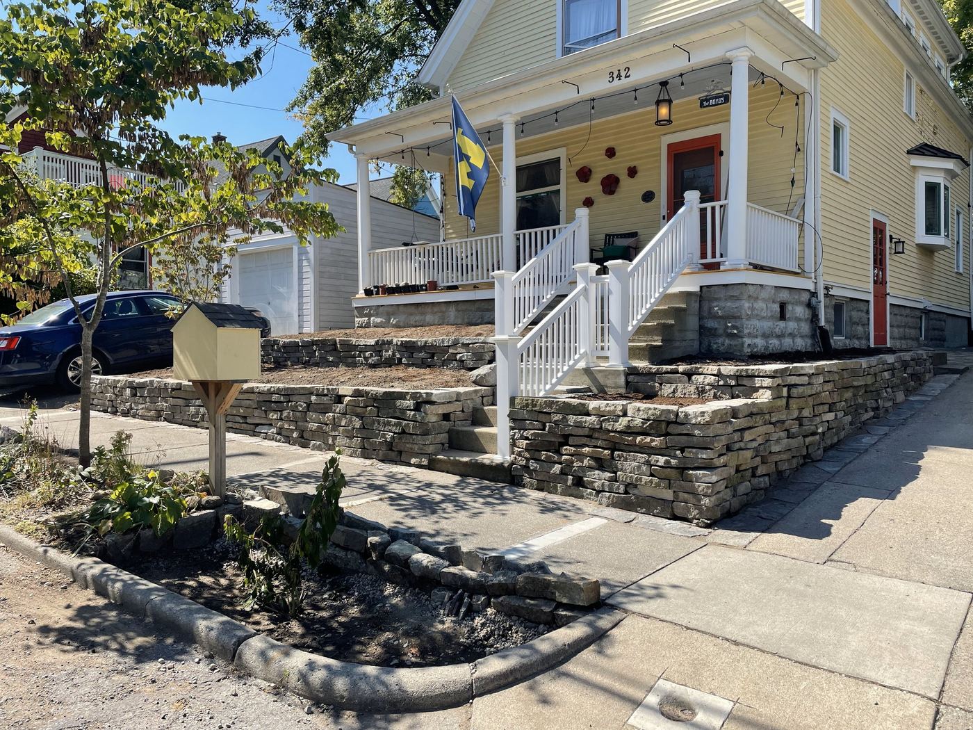 Tiered stone retaining wall and steps along a front entry