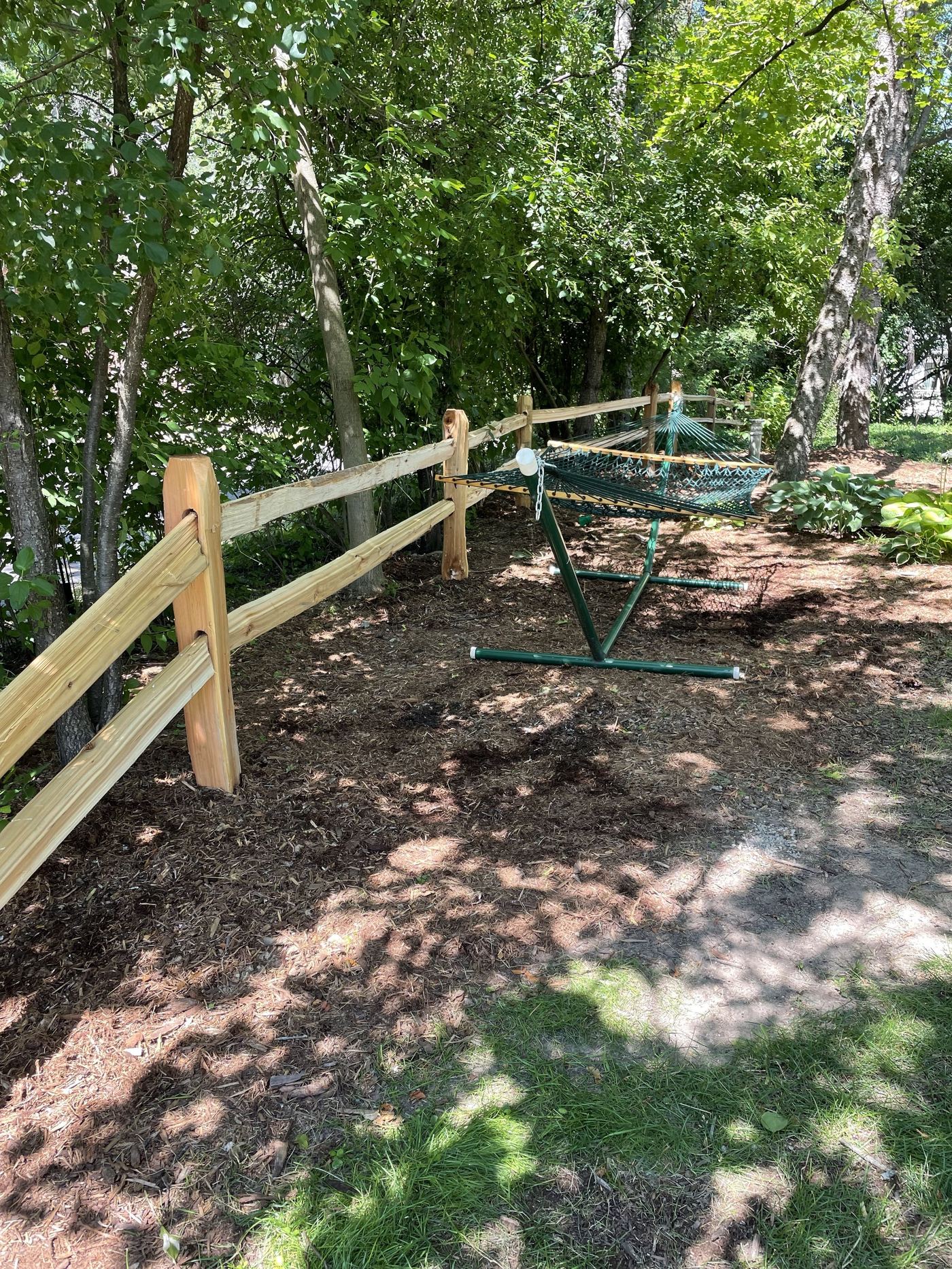 Split rail fence bordering a wooded backyard retreat